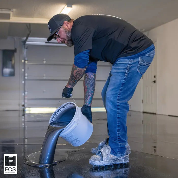 Installer pouring metallic epoxy resin from a bucket during installation