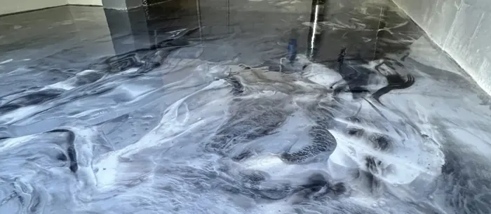 Storm-gray metallic epoxy resin floor with white cloud-like swirls